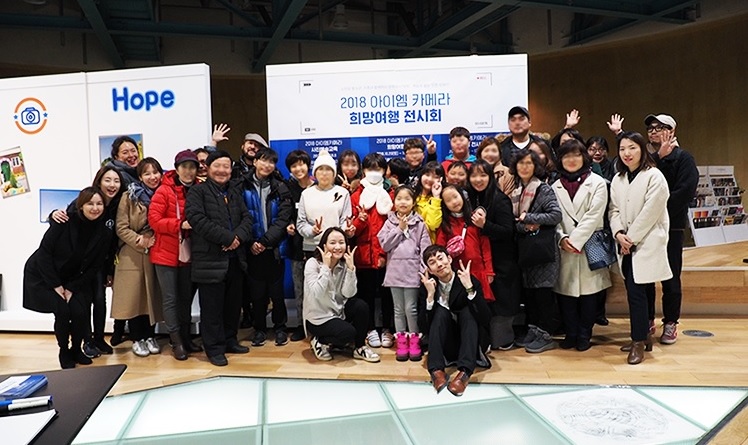 12월 17일 열린 ‘2018 아이엠 카메라 희망여행 전시회’ 오프닝 기념행사에서 ‘아이엠 카메라’ 수강생과 가족, 아티스트, 올림푸스한국과 인천문화재단, 한국문화예술위원회 관계자가 단체 사진을 촬영하고 있다.